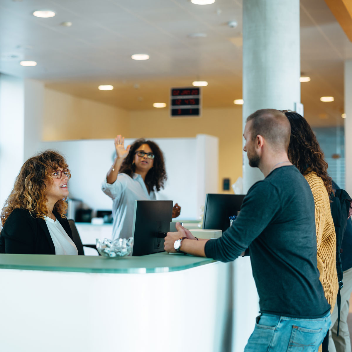 receptionist at desk talking to guests